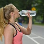 ランニングの途中で水を飲む女性